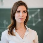 happy-teacher-standing-in-front-of-black-board-2021-08-26-15-53-07-utc.jpg